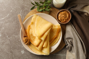 Concept of delicious breakfast with crepes with peanut butter and milk on gray table