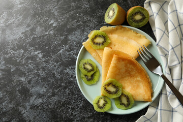 Concept of delicious breakfast with crepes with kiwi on black smokey background