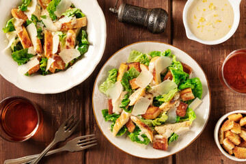 Caesar salad, top shot with wine, pepper, and the classic sauce, on a dark rustic wooden background