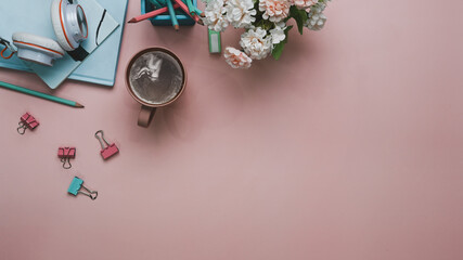 Flat lay women office desk with notebook coffee cup,pink bouquet and stationery on pastel pink background.