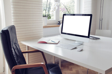 Workspace - the bright home office with the desktop computer with a blank screen on the white wooden table.