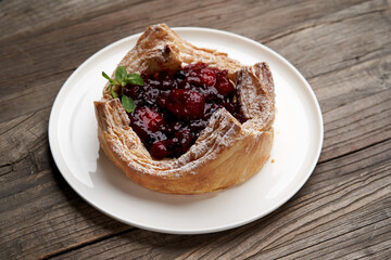 Puff pastry cake with berries on wooden background.