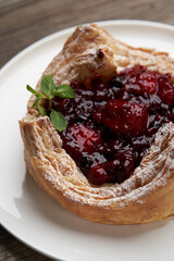 Puff pastry cake with berries on wooden background.