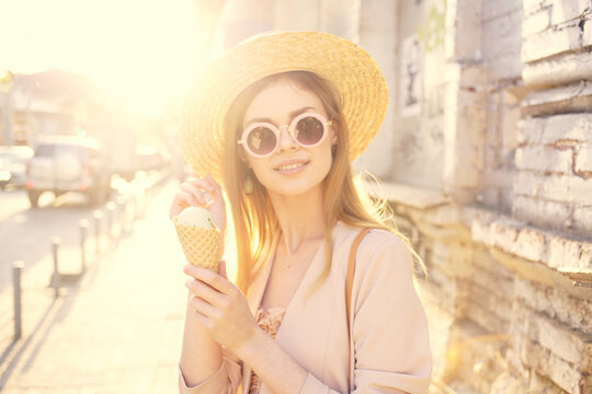 cheerful pretty woman in hat outdoors and ice cream walking in the city