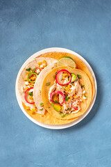 Tacos with chicken meat, avocado, and onion, shot from above on a blue background