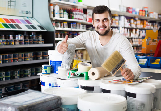 Young man buying tools for house decoration in paint supplies store