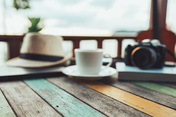 Fototapeta na wymiar wood table and Coffee, straw hat, camera blur background at resort and beach background.