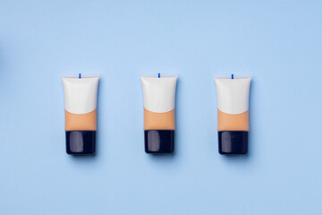 Liquid foundation tube on blue background close up