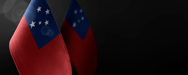 Small national flags of the Samoa on a dark background