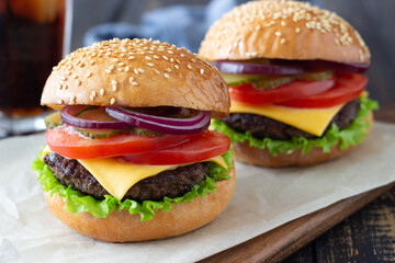 Burgers with cutlet, tomato, lettuce, cucumber, onion and cheese. American cuisine. Fast food. Cheeseburger.