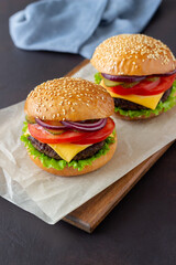 Burgers with cutlet, tomato, lettuce, cucumber, onion and cheese. American cuisine. Fast food. Cheeseburger.
