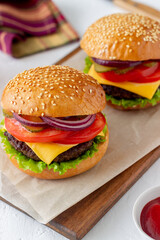 Burgers with cutlet, tomato, lettuce, cucumber, onion and cheese. American cuisine. Fast food. Cheeseburger.