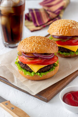 Burgers with cutlet, tomato, lettuce, cucumber, onion and cheese. American cuisine. Fast food. Cheeseburger.