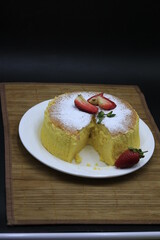 Cheesecake decorated with icing sugar, mint and strawberry in a white plate