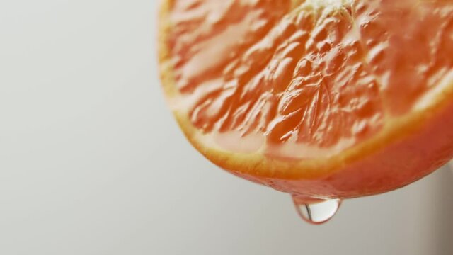 Drop of juice falls from the edge of a beautiful juicy tangerine on white background, close-up, slow motion. Healthy citrus fruits rich in vitamin C.