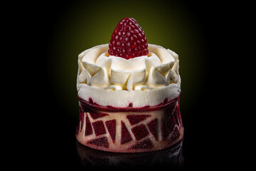 Cake basket with an ornament with cream, and on top with a raspberry on a black background with a round green gradient