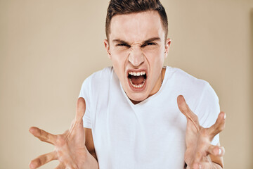 Man with displeased facial expression emotions white t-shirt gestures with hands beige background