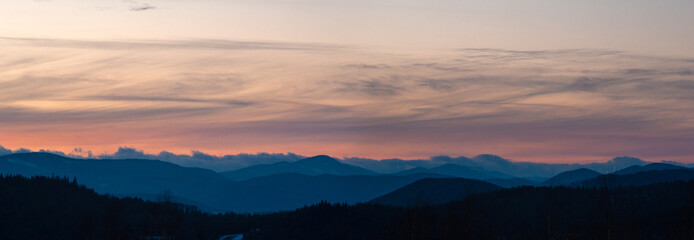Naklejka na ściany i meble Panorama of the silhouette of mountains and forest on the background of sunset