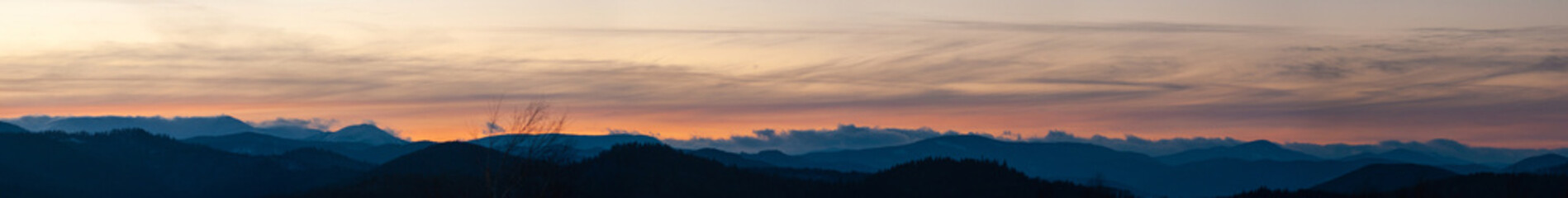 Panorama of the silhouette of mountains and forest on the background of sunset
