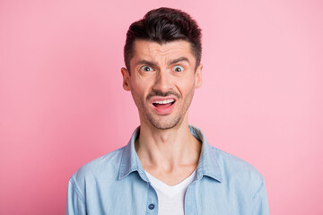 Photo of shocked irritated young brunette man negative reaction isolated on pastel pink color background