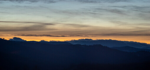 Panorama of the silhouette of mountains and forest on the background of sunset