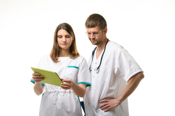 Doctor and nurse discussing the patient's tests, looking thoughtfully into the screen of a tablet computer