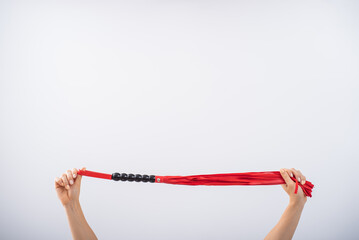 Red leather whip in female hands on a white background. Copy space.