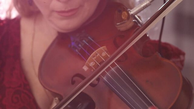 violinist playing the violin during a music concert. close-up. violinist performance on stage, light, dark background, multi-colored glare of soffits
