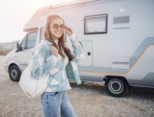 Young happy smiling woman with bag near caravan