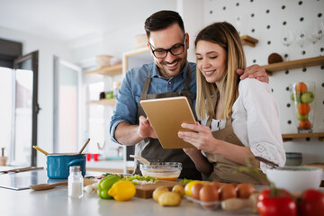 Happy young couple enjoys and having fun preparing healthy meal together at home kitchen.