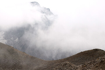 Mountain range in the clouds. Two people are walking along the ridge. Caucasus, Russia
