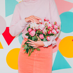 Model in pink clothes holds spring flower bouquet on colorful background. Minimal modern creative Valentines or woman's day concept. Pop art