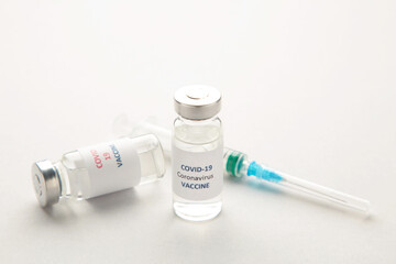 Coronavirus COVID-19 vaccine vials and syringe on grey background with copy space.