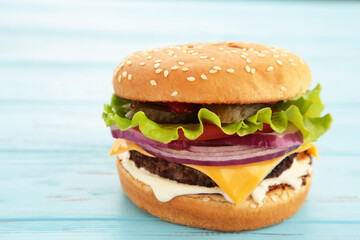 Homemade hamburger with vegetables on blue background.