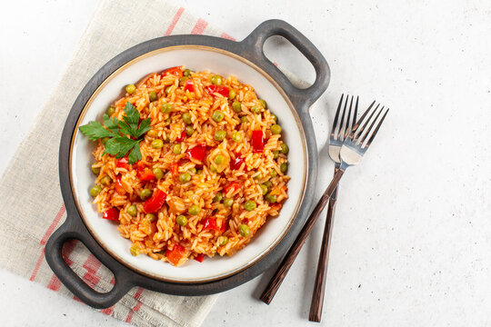 Djuvec rice - traditional balkan dish. Rice cooked with red bell pepper, tomato, peas and paprika. Light background, copy space.
