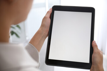 Woman using modern tablet at home, closeup. Space for design