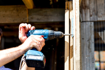 Master's hands with a screwdriver, drill. Repair, do it yourself, building a house, a barn, a summer residence, working with wood. manual labor. © Alena