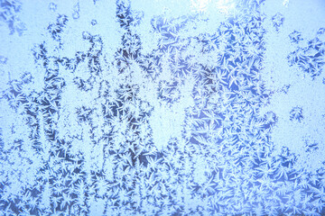 Frost on the glass of the window. Frozen window. Snowflakes on the glass in winter. Winter morning outside the window. Snowy frosty pattern on a glass surface. Background.