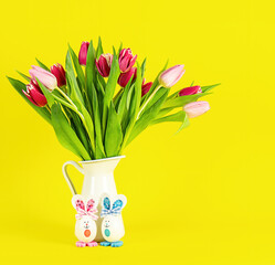 Easter greeting card with eggs bunny and tulips flowers on yellow background with copy space.
