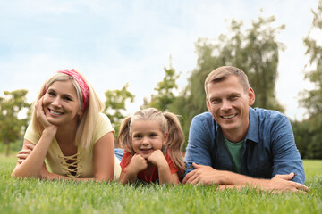 Fototapeta premium Happy family lying on green grass in park