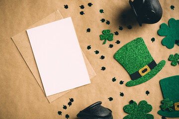 Happy St Patrick's Day concept. Flat lay, top view greeting card mockup, pots of gold, leprechaun hats, clover shamrock leaves on kraft paper background. Vintage, retro style.