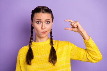 Photo of upset doubtful young lady pigtails dressed yellow sweater measure small empty space fingers isolated violet color background