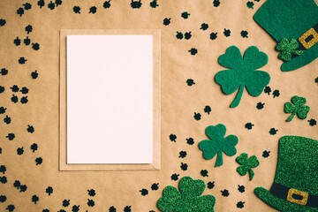 Happy Saint Patrick's Day concept. Vintage flat lay composition with blank greeting card mockup, leprechaun hats, clover shamrock leaves on kraft paper background.
