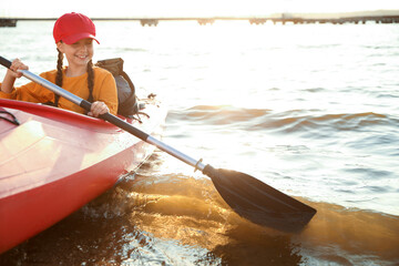 Happy girl kayaking on river. Summer camp activity