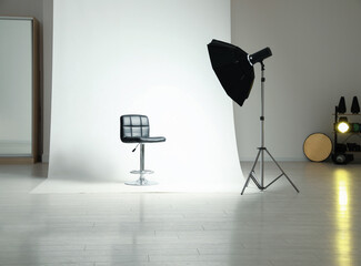 Photo studio interior with modern chair and professional lighting equipment