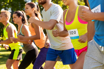 fitness, sport, race and healthy lifestyle concept - group of friends or sportsmen with badge numbers on start of running marathon outdoors