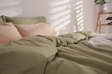 Fototapeta na wymiar Large bed with soft blanket indoors, closeup