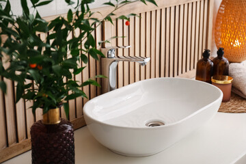 Vase with beautiful branches and candles near vessel sink in bathroom. Interior design