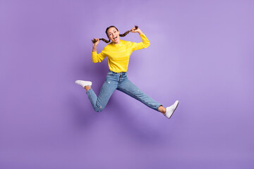 Fototapeta na wymiar Photo of charming shiny young woman hands arms braids wear yellow pullover jumping high isolated purple color background