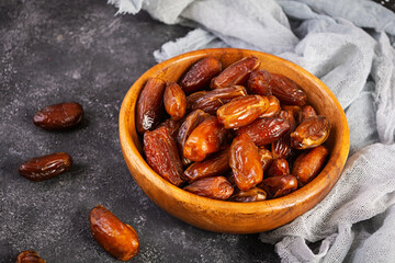 Dried date fruit in bowl on wooden background. Delicious dates fruit